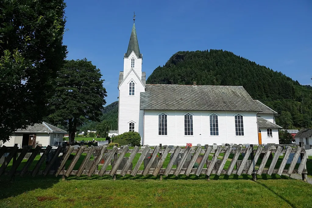 The white, wooden Strandebarm Church was built in a long church style in 1876 using designs by the architect Ole Vangberg.