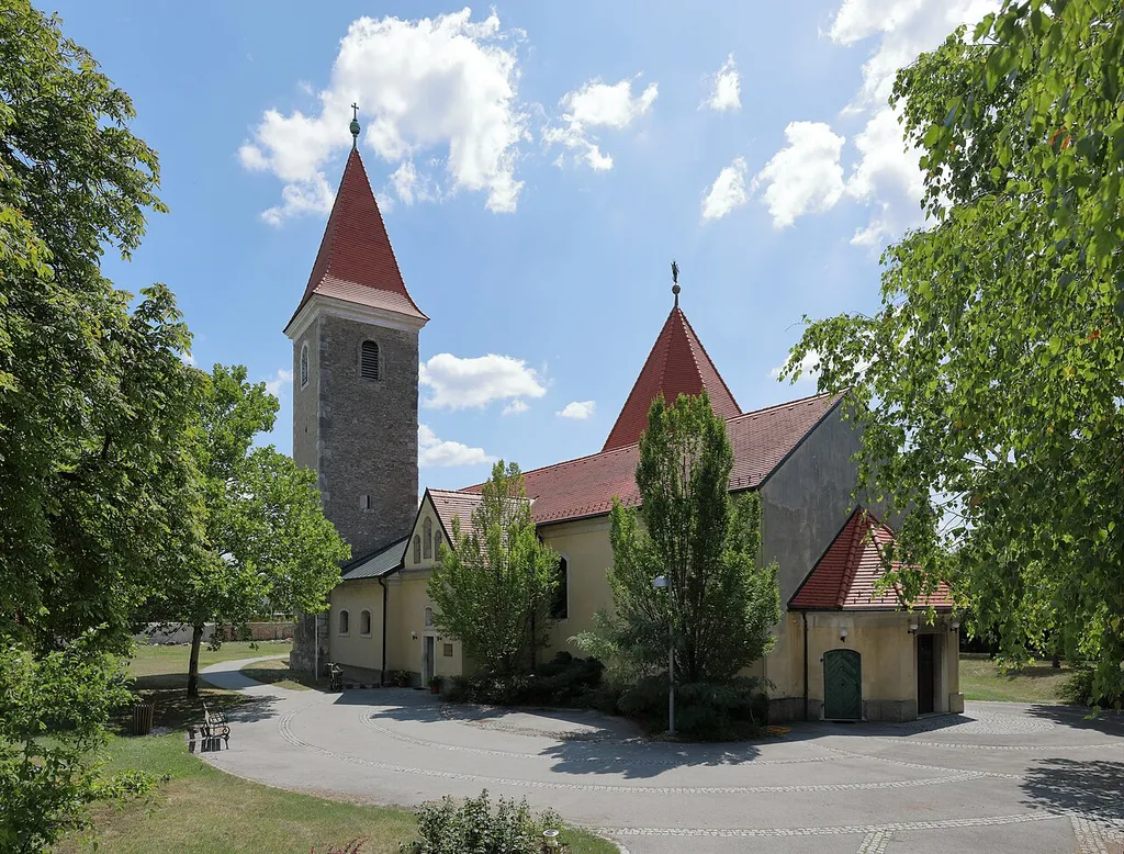 Nordwestansicht der röm.-kath. Pfarrkirche hl. Johannes der Täufer in Mannswörth, ein Ortsteil der niederösterreichischen Stadtgemeinde Schwechat.