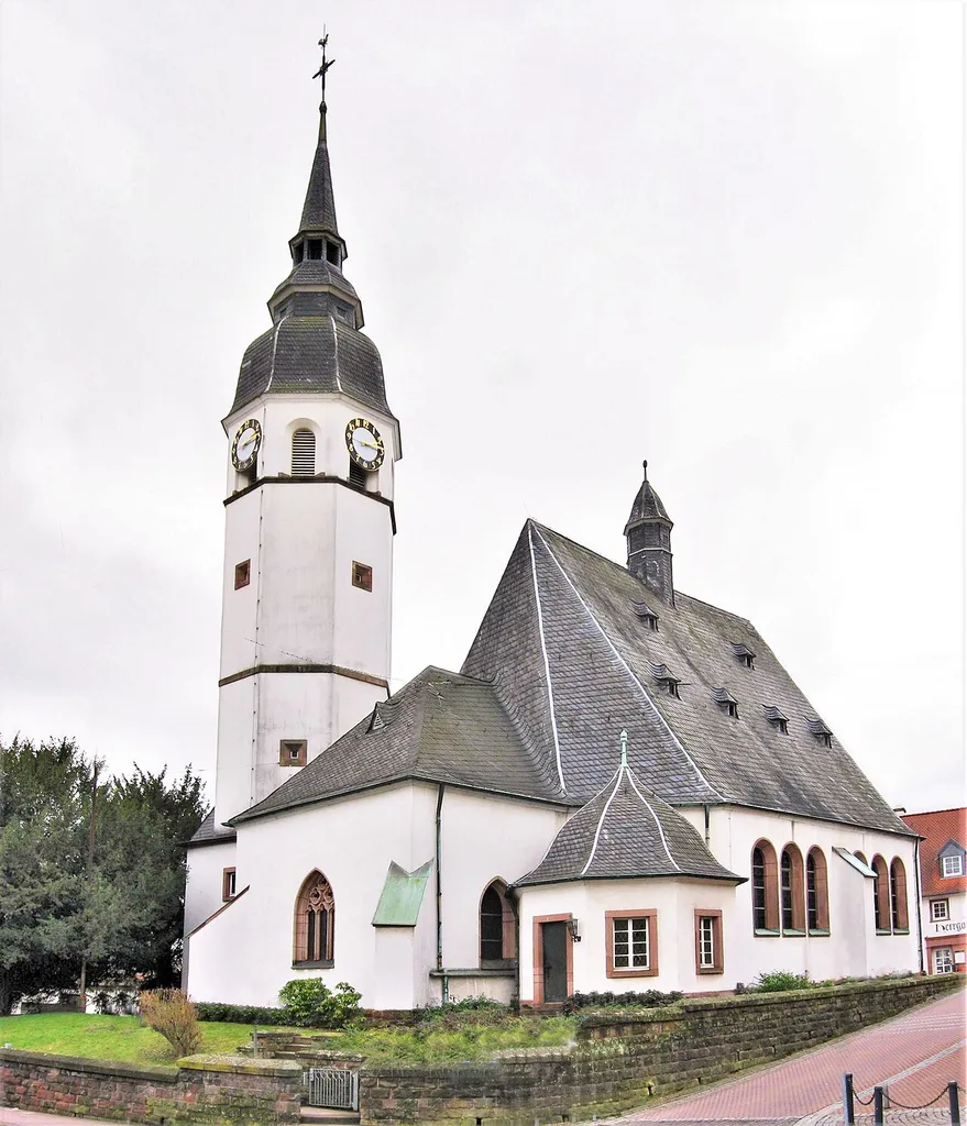 Barocke evangelische Kirche in Heusweiler. Früheste Zeugnisse stammen aus dem 12. Jahrhundert. Die Pfarrei "Husiler" wird 1330 erwähnt. Im Zuge der Reformation wurde die Kirche am 31.10.1575 lutherisch, dokumentiert im Pfarrregister von 1576. Von beiden Konfessionen wurde die Kirche ab 1685 bis zum Neubau der katholischen Kirche (1862) genutzt. Bei der Renovierung 1911 blieb der Chor aus dem 15. Jahrhundert erhalten. Das ursprüngliche barocke Kirchenschiff von 1719 wurde ersetzt. Sakristei und Turm wurden am Chor angefügt. Im klassizistischen Stil wurde der Kircheneingang gestaltet. Der Grabstein des den Neubau vorantreibenden Pfarrers Gustav Weber ist rechts vom Eingang angebracht.