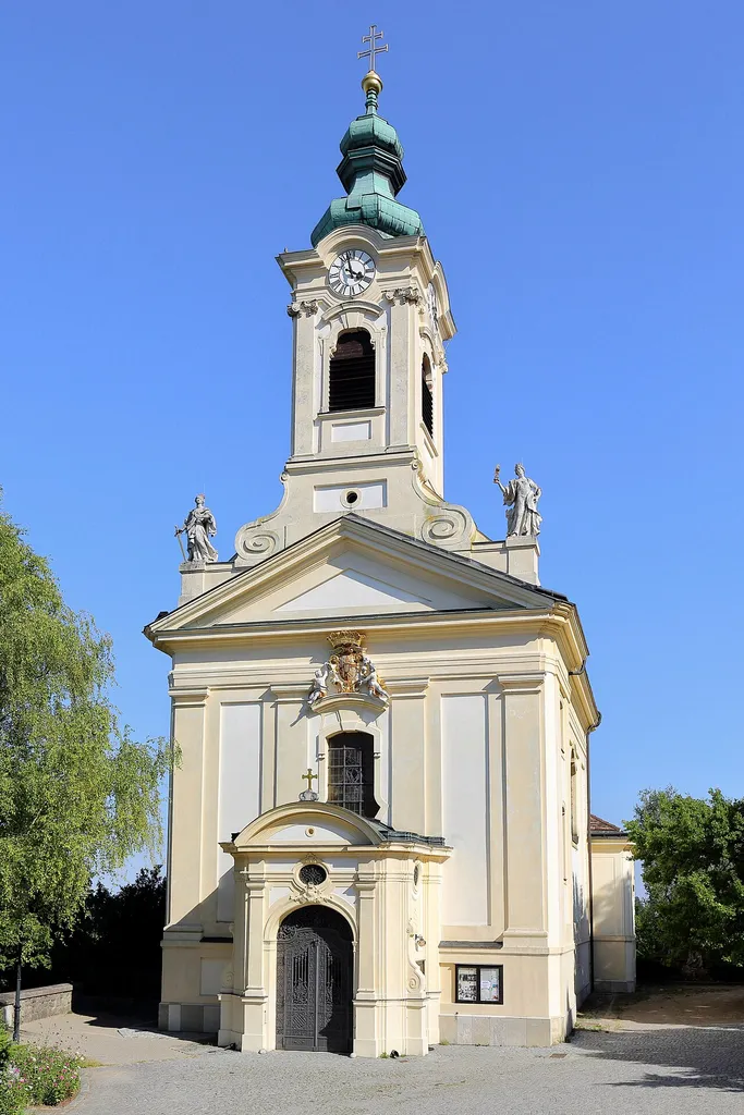 Nordwestansicht der Bergkirche Johannes der Täufer in Rodaun, ein Ortsteil des 23. Wiener Gemeindebezirkes Liesing.Die Barockkirche wurde von Eleonore von Sauberskirchen, verwitwete Rödderstahl und Besitzerin der Herrschaft Rodaun, gestiftet. Sie wurde ab 1739 vom Wiener Baumeister Johann Enzenhofer (1687-1755) auf einem künstlichen Plateau von etwa zwölf Metern Höhe errichtet und am 23. Juni 1745 geweiht. Im Jahr 1905 fügte Architekt Richard Merz einen Vorbau hinzu und veränderte die Turmfassade bzw. den Turm.