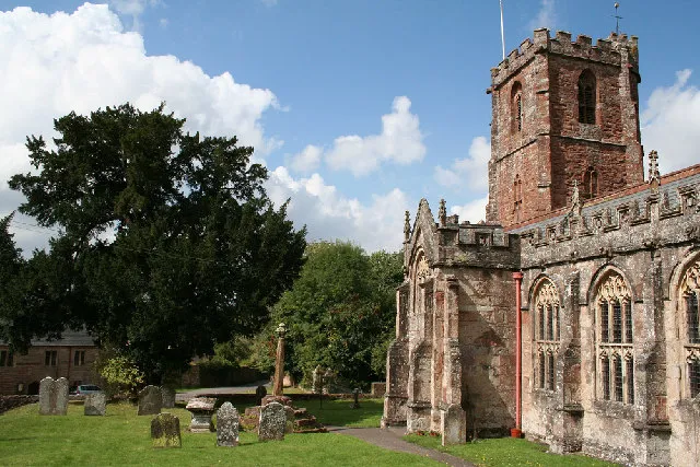 Crowcombe: Crowcombe church and cross View to the church house, beyond the yew tree, built in 1515 and the parish hall since 1977. The church, dedicated to the Holy Ghost, originally had a spire, felled by lightning in 1725 [Author's description from Geograph]