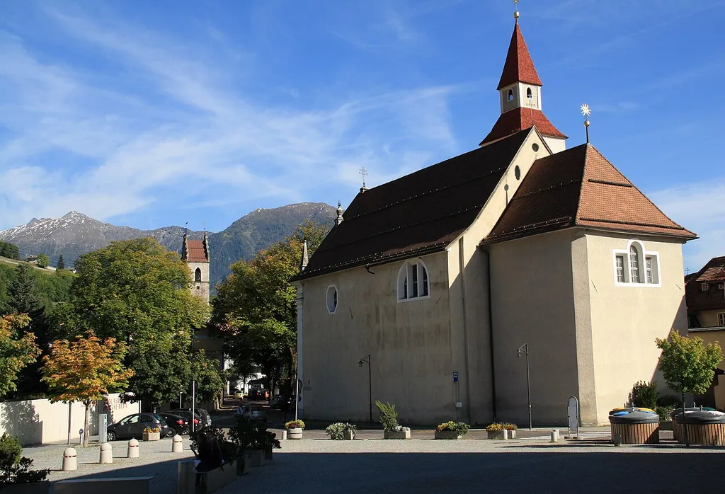 Italy, South Tyrol, Sterzing, St. Margarethenkirche. The present church was built on the initiative of the Bishop Paulinus Mayr in early Tyrolean baroque on project of Peter Delai in 1678. The old church, mentioned for the first time in 1337, was restored and enlarged between 1459 and 1463 in gothic. In 1678 was completely demolished, rebuilt and consecrated in 1681. The bell tower is detached from the church and it comes from the previous church, in 1624 the Romanic tower was demolished and built the present. The façade was inspired to renaissance with the characteristic Palladian tripartite windows. In the niches are placed the wooden sculptures of Saint Margaret and Saint Agnes and above the portal is a fresco showing the Last Supper. The imposing interior has one nave, large windows and a vaulted ceiling with lunettes. The great high altar has six columns and an altarpiece representing the Coronation of Mary painted by Joseph Renzler in 1822, beside are two wood-carving of the Saints Francis Xavier and John of Nepomuk. Above the altar on the right is placed a statue of the Madonna with Child of 17th century bordered by the Rosary formed by fifteen painted discs.