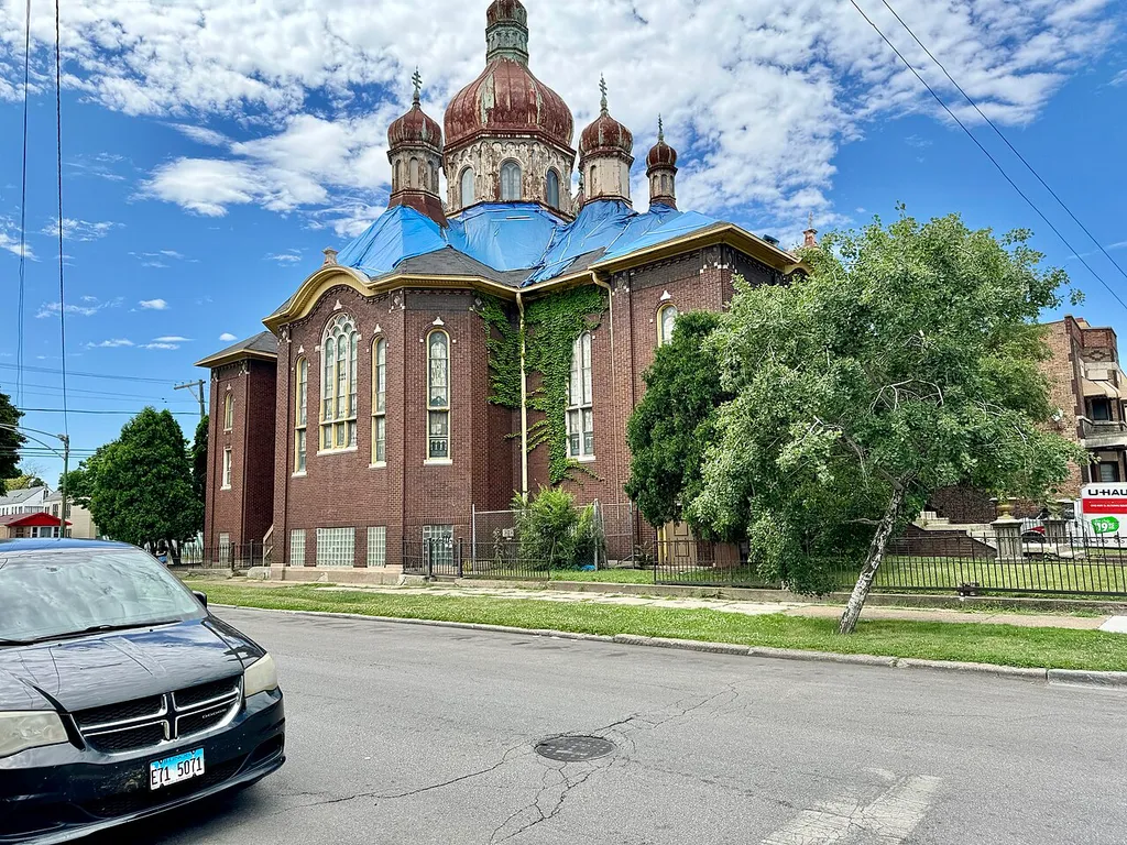 Built in 1919, this Byzantine Revival-style building was designed by Worthmann and Steinbach for the congregation of the Nativity of the Blessed Virgin Mary Ukrainian Greek Catholic Church, founded to serve the Ukrainian immigrant community in the Back of the Yards neighborhood. The building remained in use by the Ukrainian Greek Catholic congregation until 1992, when the congregation moved to a new church in suburban Palos Park, and the building was sold to the congregation of the Apostolic House Of Prayer. The building is clad in red brick with roman arched bays, a hipped roof, seven rooftop towers with onion domes and Orthodox crosses, the largest of which features roman arched windows and a large lantern, decorative patterned brickwork, terra cotta trim, a Greek Cross footprint, a circular window over the front entrance, and arched gables at the central bays of the front and side facades. The building today serves the Apostolic House Of Prayer congregation and the congregation of the Iglesia Pentecostal Unida de Chicago Illinois, and has visible signs of significant roof problems, with rusted, long unpainted towers and tarps atop the roof, which leave the future of the building uncertain and likely in jeopardy.