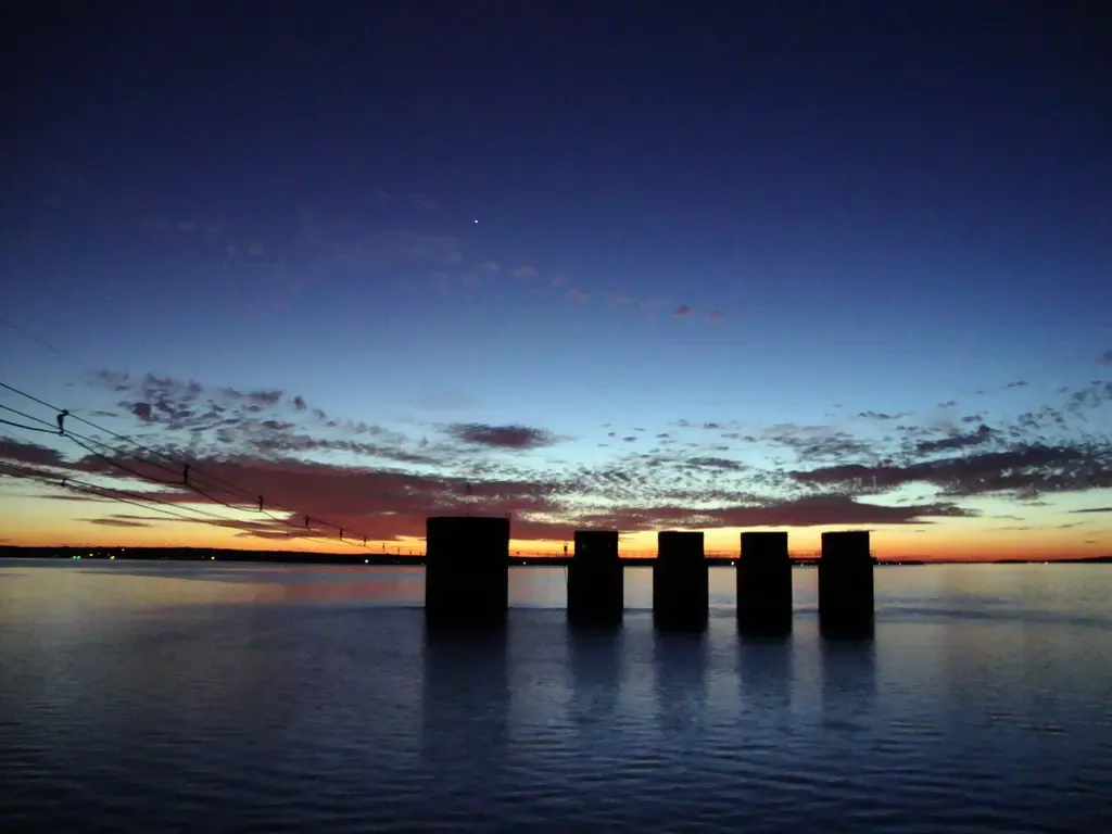 This image is a picture of Lake Murray's sunset. This sunset in this picture is beautiful because of the towers set in the middle. The towers in the image are towers used to house the mechanics that help produce hydroelectric power. The Lake Murray dam produces hydroelectric power.