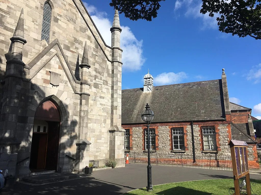 North Strand Church with infant's building of St. Columbas School in the background. The small green with a light and the notice board can also be seen.