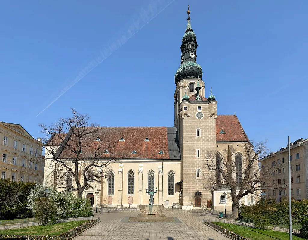 Südansicht der röm.-kath. Stadtpfarrkirche St. Stephan in der niederösterreichischen Stadt Baden und davor der Pfarrplatz mit dem 1954 errichteten Kriegerdenkmal.Die Kirche wurde in mehreren Bauphasen im 14. und 15. Jahrhundert anstelle einer romanischen Vorgängerkirche errichtet. Zerstört wurde sie um 1480 von Mathias Corvinus, bei der 1. Türkenbelagerung 1529 und bei der zweiten 1683. Nach dieser wurde der Westturm großteils abgetragen und der Hauptturm im Osten barockisiert, sowie der Zwiebelhelm mit Laterne aufgesetzt.
