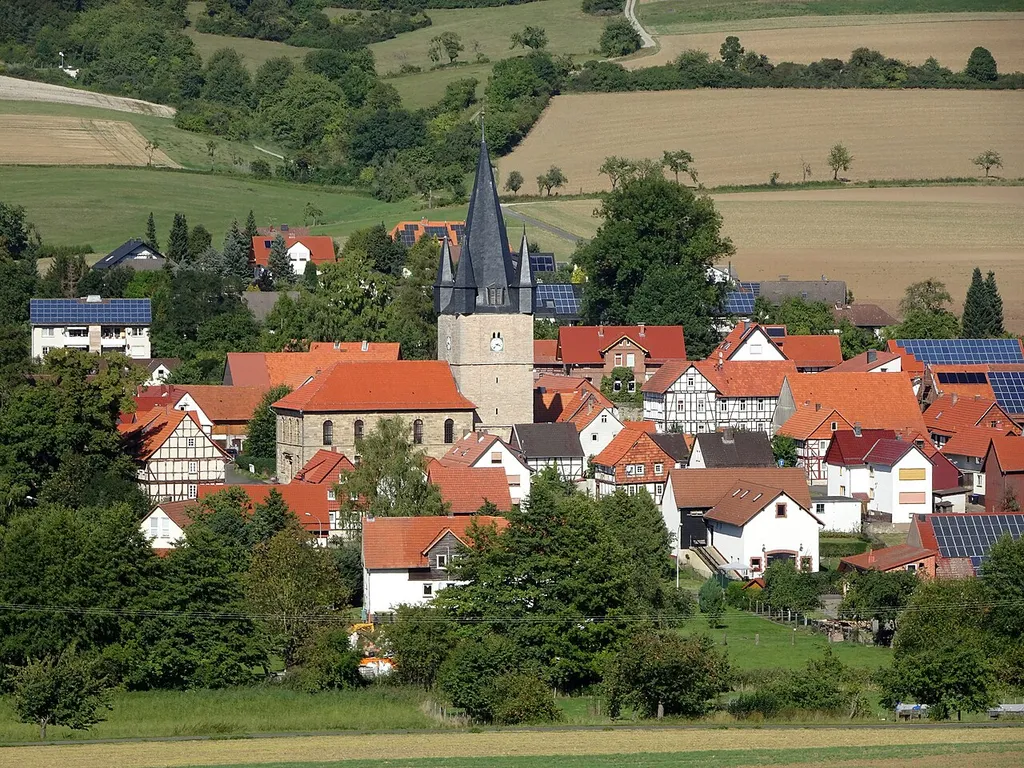 Ringgau-Netra im nordhessischen Werra-Meißner-Kreis. Blick aus südlicher Richtung auf die Kirche. "Die evangelische Pfarrkirche prägt mit ihrem markanten Turmhelm die Silhouette des Ortes Netra. Der um 1400 errichtete massive Turmcorpus wird von einem oktogonalen Pyramidendach geschlossen, dessen Diagonalseiten von kleinen Wichhäuschen besetzt werden. Das nach den Plänen A. J. Spangenbergs angesetzte Schiff in klassizistischem Formenkanon tritt neben dem überragenden Turm in den Hintergrund. Erst im Innenraum wird die gestalterische Qualität des Saales mit seinem hohen, von großzügig eingefügten Fenstern belichteten Inneren augenscheinlich. Diesen weiten Raumeindruck unterstreichen besonders die dünnen Stützen, zwischen die die Emporenbrüstungen verspannt sind." Text aus: Denkmaltopographie Bundesrepublik Deutschland, Kulturdenkmäler in Hessen. Werra-Meißner-Kreis I, Altkreis Eschwege. Peer Zietz, Thomas Wiegand, Braunschweig: Vieweg Verlag, 1991, ISBN 3-528-06240-1. Durch Netra führen der Herkules-Wartburg-Radwanderweg und der Elisabethpfad.