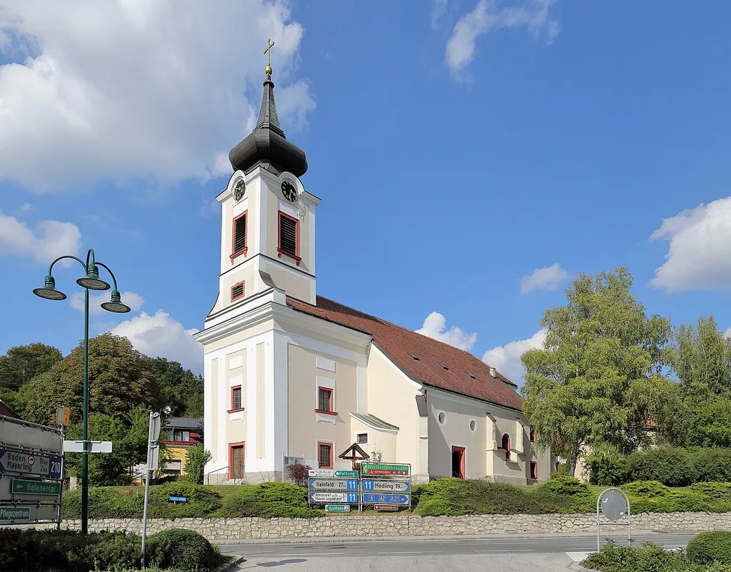 Südansicht der röm.-kath. Pfarrkirche hll. Georg und Margarethe der niederösterreichischen Gemeinde Alland.Ursprünglich eine romanische Saalkirche. Im 12. Jahrhundert wurde diese um ein Nordschiff und einen Westturm erweitert. Im 14. Jahrhundert erfolgte der Anbau der Südostkapelle, die Einwölbung des Nordschiffes sowie der Neubau des Chores. Um 1500 Zubau eines 2. südlichen Seitenschiffjoches und des Südportales. Um 1800 Neubau der oberen Geschosse des Turmes und Barockisierung der Fassade. Im Zuge der Kriegshandlungen 1945 stürzte das zweijochige Mittelschiff und das Südschiff ein und wurde bis 1954 wiederaufgebaut. Bei den zwei Türkenbelagerungen (1529 und 1683) wurde die Kirche ebenfalls schwer beschädigt und jeweils wiederinstandgesetzt.