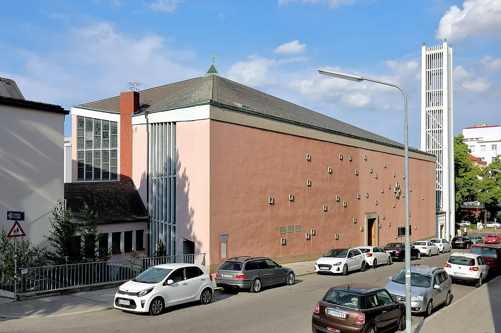 Westansicht der röm.-kath. Pfarrkirche Maria, Mutter der Gnaden an der Adresse Heiligenstädter Straße 101 in Unterheiligenstadt, ein Wiener Stadtteil im 19. Bezirk Döbling. Der zweistöckige Saalbau mit einem Grundriss in Form eines gleichseitigen Dreiecks sowie abgerundetem Chorraum und Zeltdach wurde ab 1965 nach Plänen des Architekten Carl Müller und seines Sohnes errichtet und am 5. November 1966 geweiht.