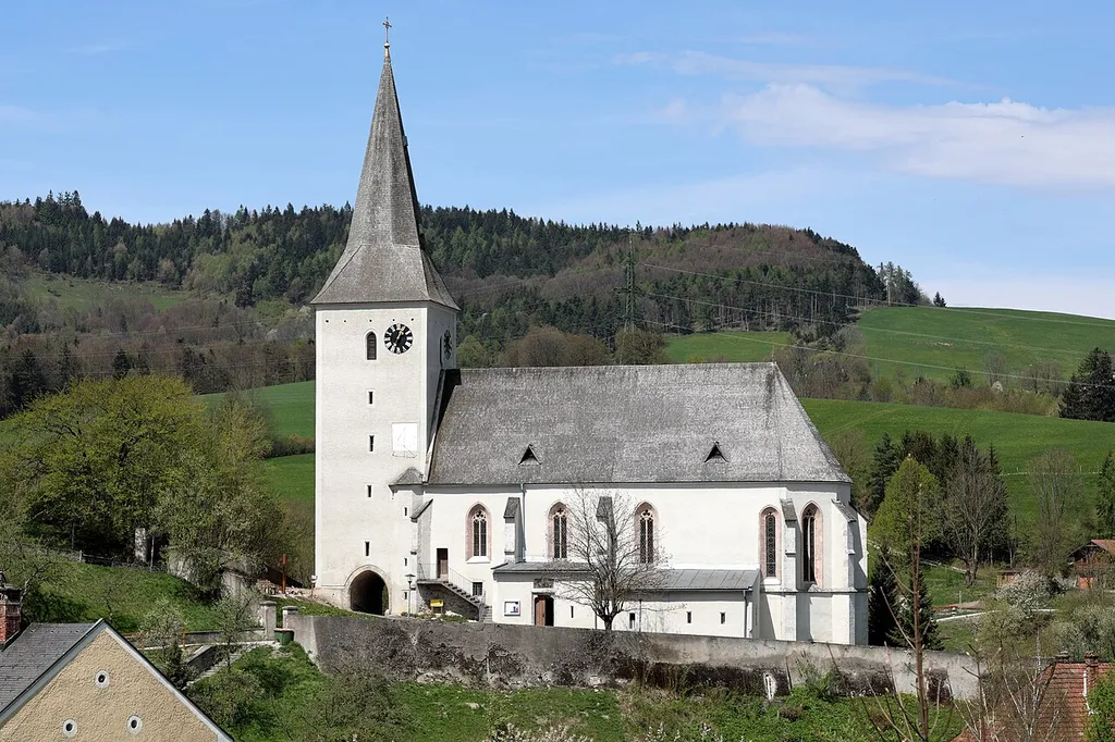 Südansicht der röm.-kath. Pfarrkirche hl. Michael in der niederösterreichischen Marktgemeinde Kaumberg. Eine in erhöhter Lage in mehreren Bauetappen errichtet gotische Saalkirche mit einem mächtigen spätgotischen Westturm (mit 1502 datiert) und die teilweise von einer Wehrmauer umgeben ist.