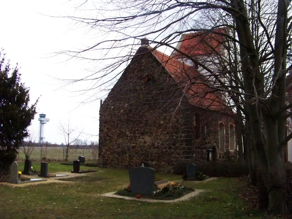 Kirche in Kursdorf, dahinter der Tower des Flughafens