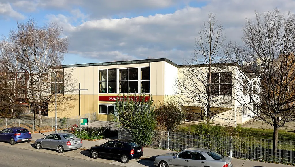 Westansicht der röm.-kath. Pfarrkirche Don Bosko mit dem südseitig angebauten Pfarrzentrum in der Herzmanovsky-Orlando-Gasse im 21. Wiener Gemeindebezirk Floridsdorf. Die Kirche wurde nach Plänen des Architekten Clemens Holzmeister ab 1970 im Osten der neugebauten Großfeldsiedlung errichtet und am 28. November 1971 durch Bischof Franz Jachym geweiht.