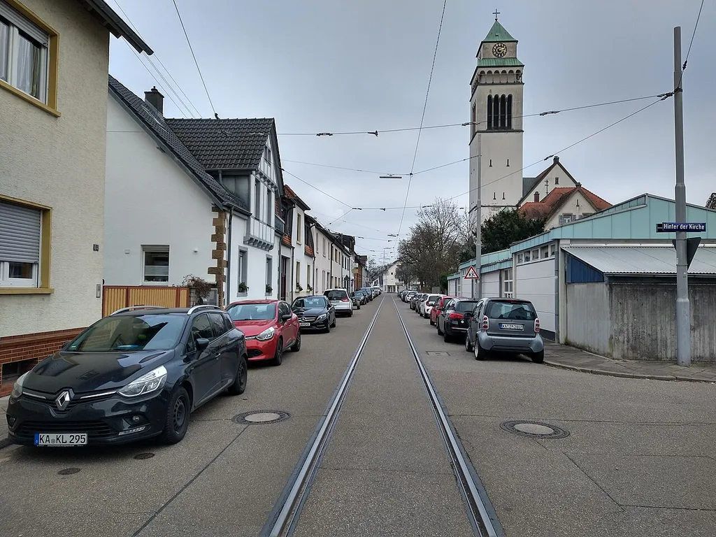 As part of tram track replacement works in Karlsruhe-Daxlanden, the overhead line on Kastenwörtstraße has been temporarily removed. The suspension lines partly anchored to house walls are still in place.