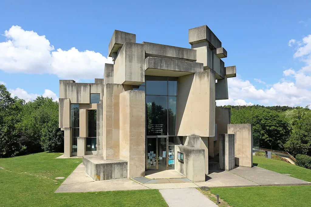 Ostansicht der Wotruba- bzw. Dreifaltigkeitskirche auf dem Georgenberg im Wiener Stadtteil Mauer des 23. Gemeindebezirkes Liesing.Die Kirche im Stil des Brutalismus wurde auf Initiative von Margarethe Ottillinger (1919–1992) und nach einer Idee des Künstlers Fritz Wotruba (1907–1975) vom Architekten Fritz Gerhard Mayr (* 1931) errichtet. Der Entwurf für die Kirche (152 Betonblöcke mit einen Gesamtgewicht von über 4000 Tonnen, ohne Symmetrie aufeinander geschachtelt, mit schmalen, verschieden hohen Fensteröffnungen) wurde von Wotruba 1964 präsentiert. Wegen großem Widerstand konnte man erst 1974 mit dem Bau beginnen und zwei Jahre später, am 24. Oktober 1976, erfolgte die feierliche Einweihung durch Kardinal Franz König.