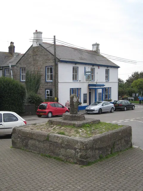 Stone cross in St Buryan Situated just outside the church gates. In the background is the St Buryan Inn. The village featured in the controversial 1971 Sam Peckinpah film 'Straw Dogs'.