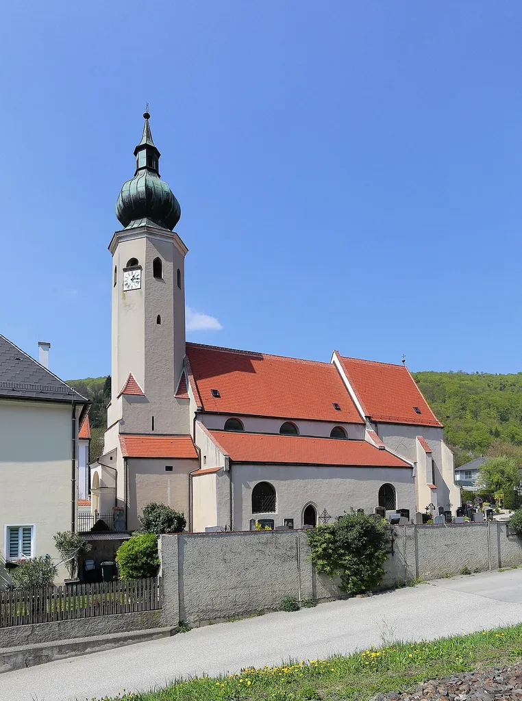 Südostansicht der römisch-katholischen Pfarrkirche Mariae Himmelfahrt in Aggsbach Markt, ein Ortsteil der niederösterreichischen Marktgemeinde Aggsbach. Eine spätromanische, dreischiffige Basilika mit gotischem Gewölbe und Chor, die 1779 barockisiert wurde.
