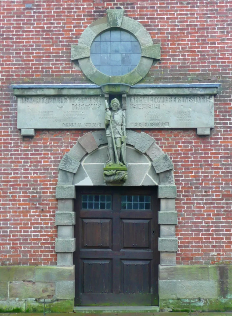 West entrance of St Peter's parish church, Marchington, Staffordshire, with the First World War memorial above the door. Figure of St. George and dragon at his feet. The memorial reads In ever grateful memory of those who laid down their lives in the great war 1914-1919 T. Bennett E. Buckley W. Champion W. Cotterill G. Charlesworth A. Gilbert J. Gilbert R. Gilbert H. Hamilton T. Harper S. Harrison H. Hollins T. Thomas W. Walker F. Williams Their name liveth for evermore
