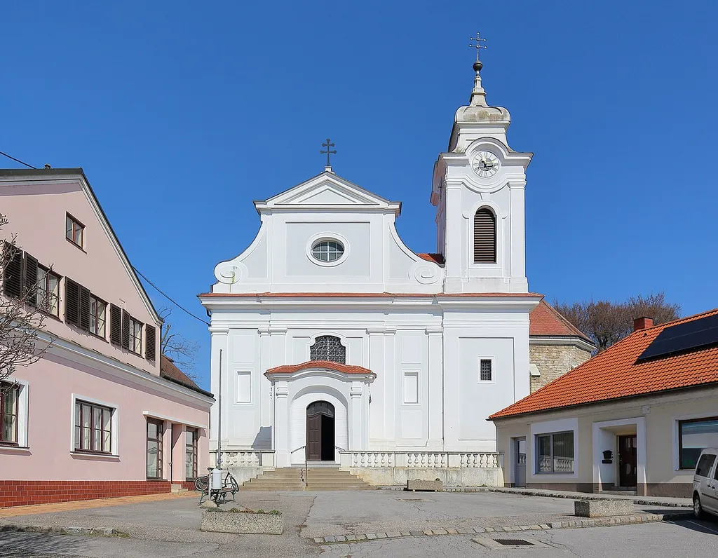 Haupt- bzw. Südfassade der römisch-katholischen Pfarrkirche hl. Nikolaus in der niederösterreichischen Marktgemeinde Wilfersdorf.Eine spätbarocke Saalkirche, die von 1742 bis 1744 von Andreas Hammer errichtet wurde. Der Chor der ehemaligen gotischen Pfarrkirche Maria Himmelfahrt wurde in den Sakralbau integriert, schließt ostseitig an das Langhaus an und dient als Kapelle.