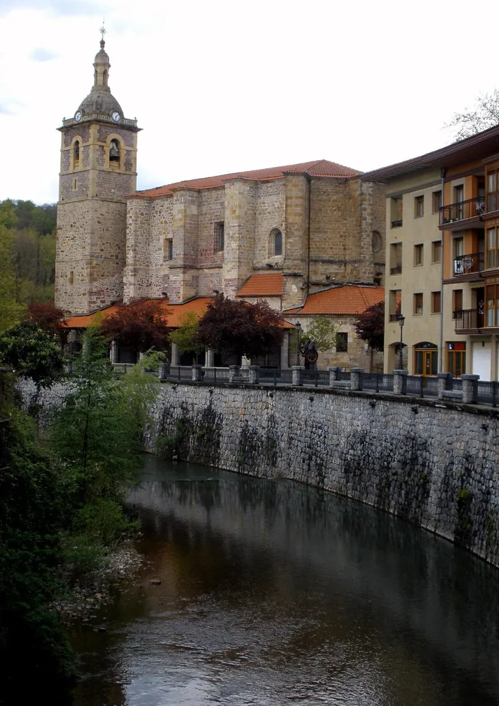 El río Agauntza, a su paso por el centro de Lazkao. Al fondo, la iglesia parroquial de San Miguel (Guipúzcoa, País Vasco, España)
