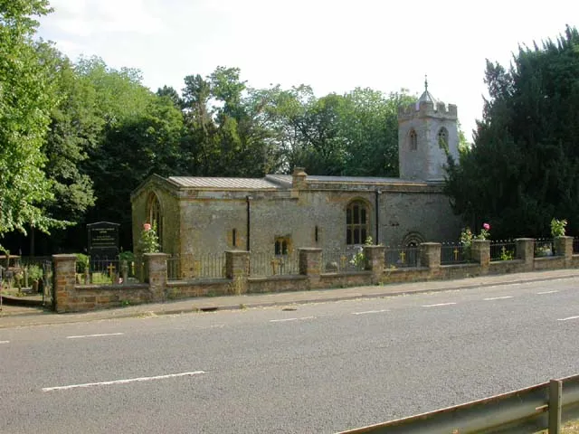 St Michael's Church, Upton. The black noticeboard with gold writing to the left of the church states that the building is in the care of the Churches Conservation Trust. Picture taken from the central strip of the A4500 dual carriageway.