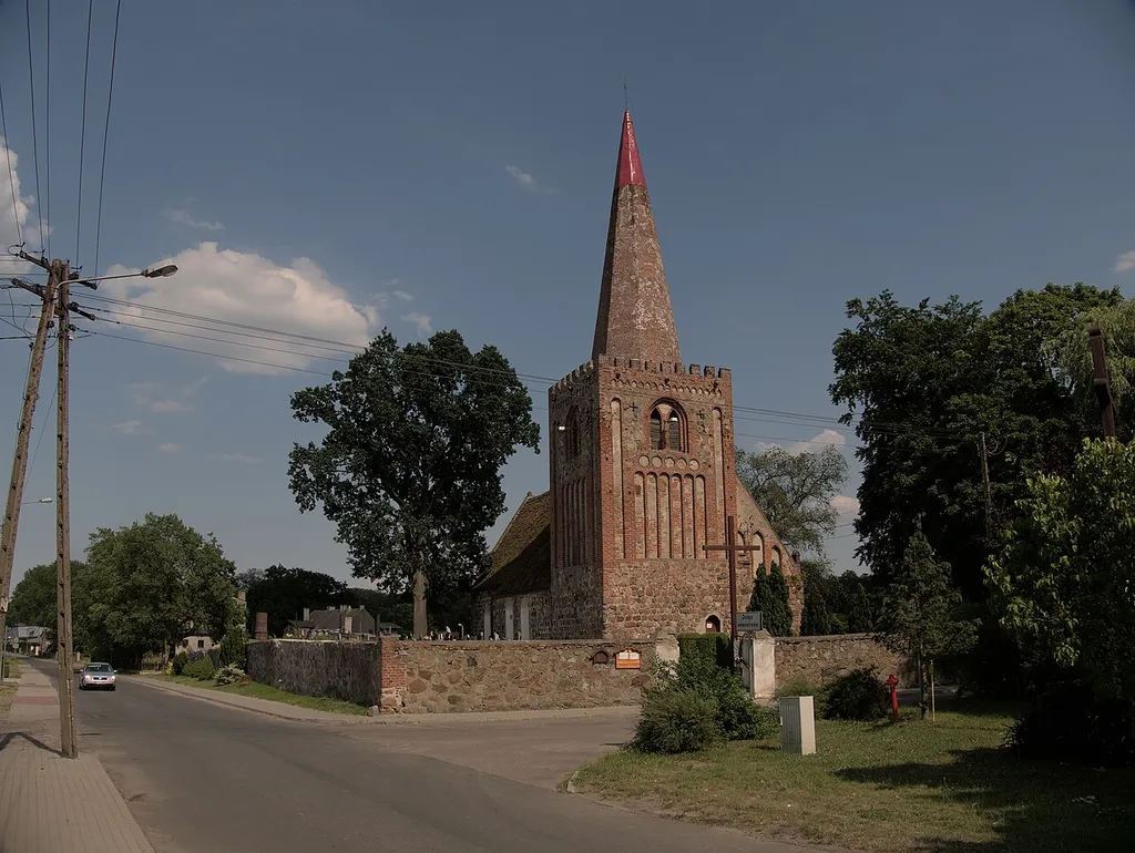 Blick auf die Dorfkirche Nowielin von der davorliegenden Kreuzung gesehen, Kirchturm und Kirchhof-Mauer.