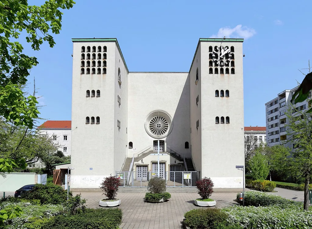Südansicht der röm.-kath. Pfarrkirche Königin des Friedens an der Adresse Buchengasse 158 im 10. Wiener Gemeindebezirkes Favoriten.Der moderne Stahlbeton-Sakralbau wurde ab Herbst 1933 (Grundsteinlegung am 3. September 1933) nach Entwürfen der Architekten Leo Schmoll und Robert Kramreiter errichtet und am 16. November 1935 eingeweiht. Die Kirche hat eine Länge von 52 Meter und eine Breite von 22 Meter. Die Höhe des Kirchenschiffs beträgt 16,5 Meter und ihr maximales Fassungsvermögen beläuft sich auf etwa 3000 Personen, davon 480 Sitzplätze.