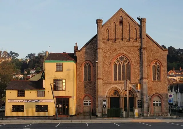 St Leonard's church, Newton Abbot Rebuilt here in 1835, leaving a medieval tower just over 100 metres nearer the town centre as all that remains of a chapel of ease. Together with the junk shop next door, it bathes in the last of the evening sunlight. Seen from the Asda car park.