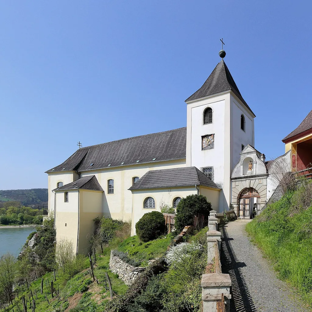 Südostansicht der ehemaligen Serviten-Klosterkirche und Pfarrkirche von Schönbühel, ein Ortsteil der niederösterreichischen Marktgemeinde Schönbühel-Aggsbach.Die lang gestreckte, schmale und einschiffige Kirche wurde im Zuge der Klostererrichtung in der 2. Hälfte des 17. Jahrhunderts gebaut. Ursprünglich war das Pfarrrecht bei der Kapelle des Schlosses Schönbühel, 1786 wurde es auf die Klosterkirche übertragen und 1980 erfolgte die Auflösung des Klosters.