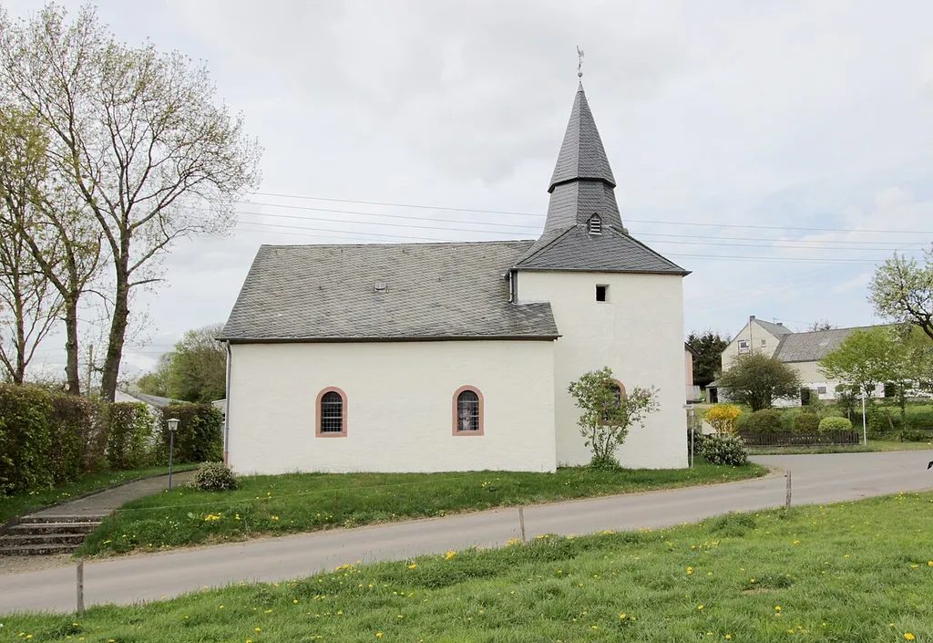 54673 Krautscheid, Kapellenstraße 1. Zweiachsiger Saalbau mit Chorturm, im Kern wohl romanisch (spätgotischen Rippen, Rundkonsolen und Wandsäulchen). Das einfache Schiff erhielt eine Holzlehmdecke mit Voute. Der einfache hölzerne Säulenaltar d. 18. Jahrhundert zeigt ein großes Mittelbild und seitliche Konsolen für die Figuren der heiligen Apollonia und Gertrud. Aufnahme von 2018.