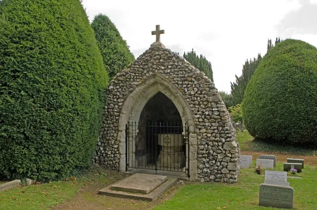 Open-fronted baptistry on the grave of Rev Ferdinand Faithful in St Mary's parish churchyard, Headley, Surrey. Designed in the 19th-century by GE Street, using a 15th-century arch from the from the demolished parish church.