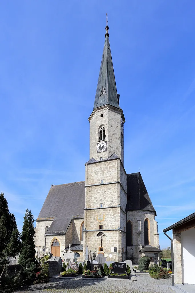 Südostansicht der katholischen Pfarrkirche Mariä Himmelfahrt in der oberösterreichischen Gemeinde Kirchdorf am Inn. Ein gotischer Tuffsteinbau mit einem mächtigen Turm im südlichen Chorwinkel, einem einschiffigen, dreijochigen Langhaus und einem leicht eingezogenen, zweijochigen Chor (datiert mit 1486).