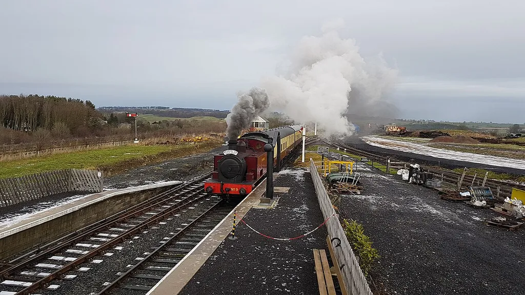 View N of Hudswell Clarke 0-6-0T no. 9 "Richboro" approaching platform 1 of the Aln Valley Railway's Lionheart Station on 20 December 2017. Lionheart Signal Box and the western headshunt can be seen in the background to the left and the junction signal and eastern headshunt in the background to the right. Taken from Lionheart footbridge.