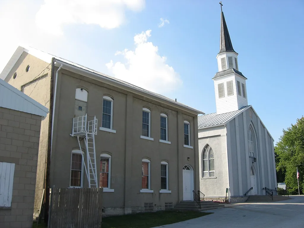 Front of St. John Catholic Church and Parish Hall, located along Van Buren Street in the community of Fryburg in Pusheta Township, Auglaize County, Ohio, United States. Built in 1850, the complex was listed on the National Register of Historic Places as a part of the Cross-Tipped Churches of Ohio Thematic Resources.
