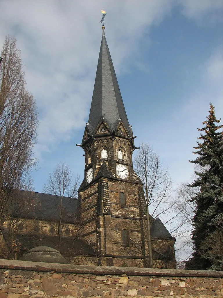 Der Kirchturm der Lutherkirche im Stadtteil Döhlen der Stadt Freital in Sachsen. Der Turm wurde vom Johann-Georg-Palitzsch-Hof aus aufgenommen. Die Uhr ist funktionstüchtig und zeigt die aktuelle Zeit. Der untere Gebäudeteil der Kirch wird von der Kirchmauer verdeckt. Auf der Turmspitze befindet sich ein Kreuz.