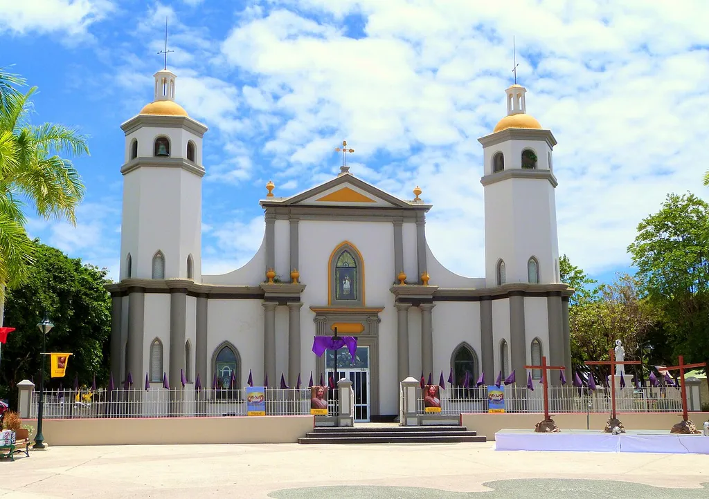 The historic Iglesia de San Juan Bautista y San Ramón Nonato (construction begun 1807), located on the town plaza in Juana Díaz, Puerto Rico, is listed on the U.S. National Register of Historic Places. In this photo, the church and square bear decorations in preparation for Good Friday. This is an image of a place or building that is listed on the National Register of Historic Places in the United States of America. Its reference number is 84000465 (Wikidata).