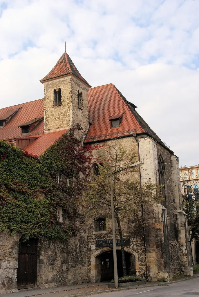 Profanierte Kirche St. Peter und Paul, ehem. Pfarrkirche des Stifts Niedermünster, Saalbau mit die römische Mauer überragendem Rechteckchor, Walmdach und Chorflankenturm, 2. Viertel 13. Jh., Umgestaltungen um 1510 und Mitte 17. Jh.; westlich Wohnhaus viergeschossiger und traufständiger Frackdachbau, 16. Jh.; Mauerstück der röm. Legionslagermauer, 179 n. Chr. This is a photograph of an architectural monument.It is on the list of cultural monuments of Bayern, no. D-3-62-000-388.