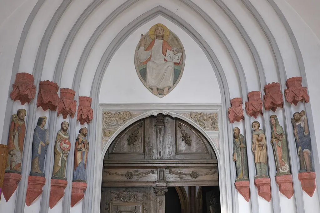 Katholische Pfarrkirche St. Johannes Baptist in Nabburg im Landkreis Schwandorf in der Oberpfalz (Bayern/Deutschland), Portal aus dem zweiten Viertel des 14. Jahrhunderts, originale Zwickelreliefs, moderne Gewände- und Tympanonfiguren