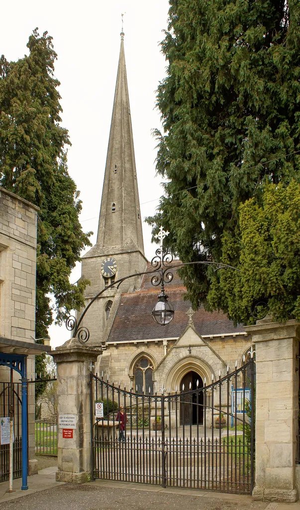 South porch, west tower and broach spire of St Laurence' parish church, Stroud, Gloucestershire, seen through the south gateway to the churchyard