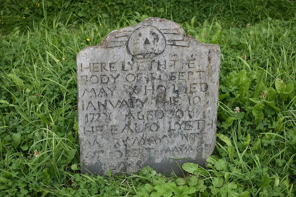 The inscription reads: "HERE LYETH THE / BODY OF ROBERT / MAY WHO DIED / JANUARY THE 10th / 1728 AGED 70 Yrs. / HERE ALSO LYETH / MARY MAY Ye WIFE / OF ROBERT MAY AGE / 71 YEARS."