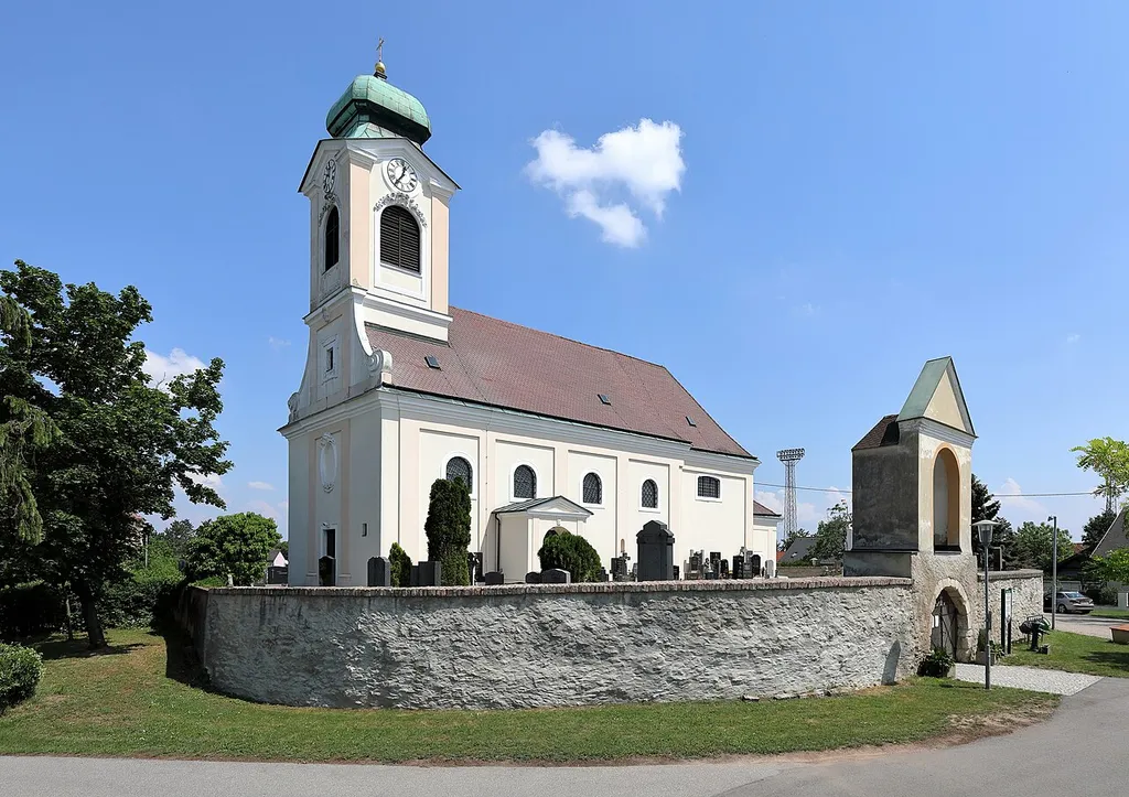 Südwestansicht der röm.-kath. Pfarrkirche hl. Veit in der niederösterreichischen Gemeinde Untersiebenbrunn.Die in erhöhter Lage errichtete Kirche ist von einem Friedhof mit Mauer umgeben. Die barocke Kirche wurde 1710 anstelle einer mittelalterlichen Wehrkirche, die zuvor großteils abgetragen wurde, errichtet.