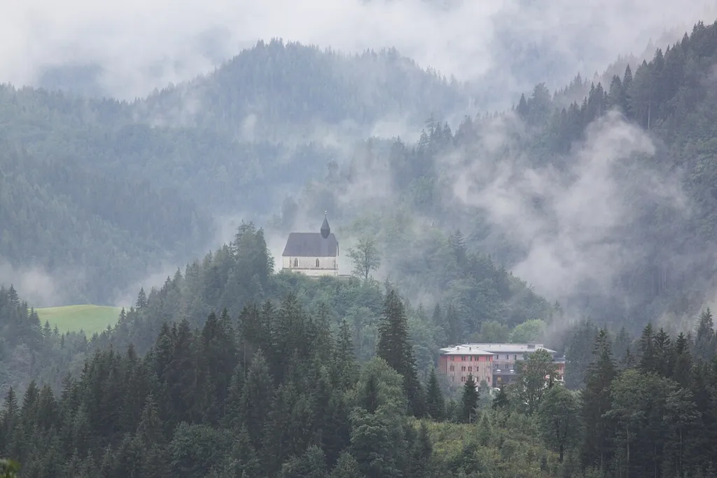 Kath. Filialkirche hl. Sigmund mit Kirchhof, rechts davon etwas tiefer JUFA Mariazell Familien-Resort Sigmundsberg