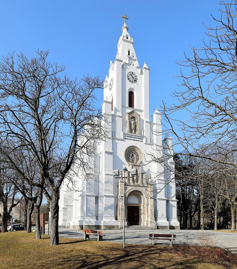 Ostsüdostansicht der röm.-kath. Stadtpfarrkirche hl. Jakobus der Ältere in der niederösterreichischen Stadtgemeinde Bad Vöslau.Die gewestete Saalkirche mit dominanter Osturmfassade im romantischen Rundbogenstil am Übergang zum strengen Historismus wurde von 1860 bis 1870 nach Plänen des Architekten Franz Sitte errichtet. Die vom Grafen Moritz II. von Fries (1804–1887) gestiftete Kirche ist das Hauptwerk des Architekten und ist der bedeutendste Sakralbau der Zeit im südlichen Niederösterreich.