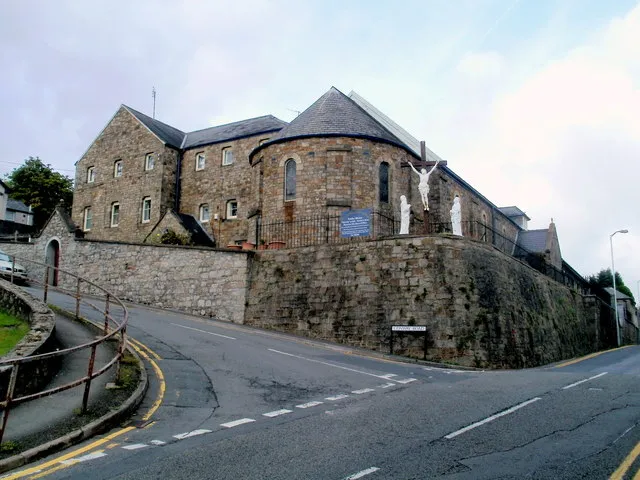 Grade II listed St Albans Catholic Church, Pontypool. Located on the corner of George Street and Conway Road. The church website shows that the church was built in 1844-46 in an economical version of the then fashionable Norman style, to the design of J.J. Coles, a prolific Catholic architect. It is built of squared coarse brown limestone rubble with a Welsh slate roof. The church is aligned NW/SE. The church features an early 20th century gabled dormer with lattice casement over the doorway. The apse has five windows with pilasters between a conical roof. The church was refurbished in 1958. Grade II listed in August 1997.