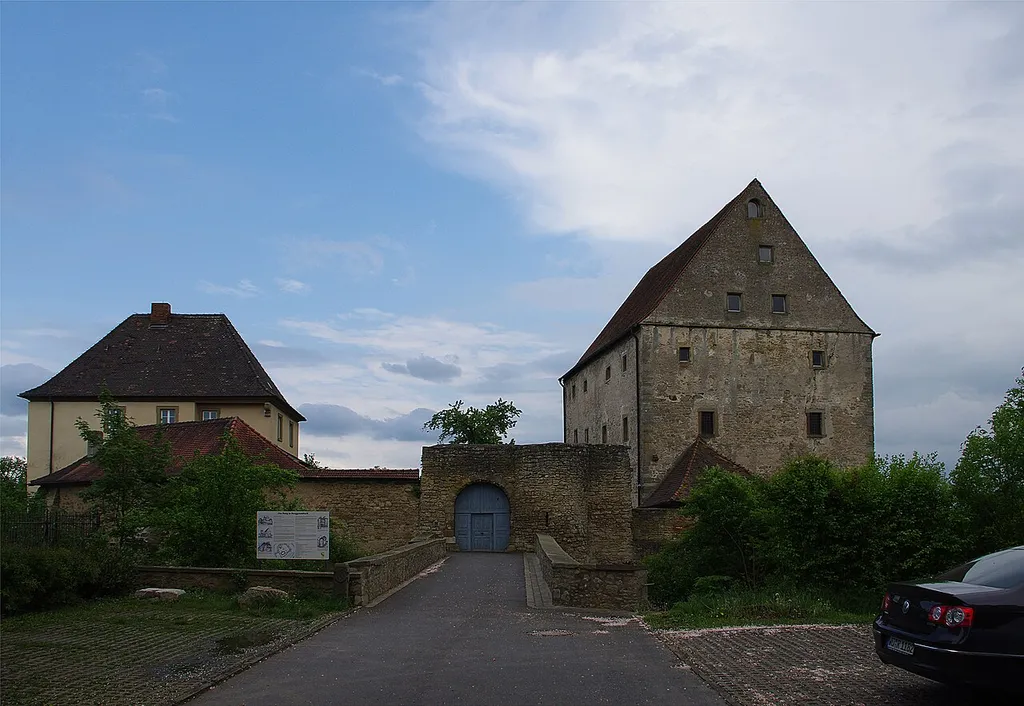 Ehemaliges Schloss der Herren von Grummbach, ab 1243 im Besitz der Grafen Rieneck-Rothenfels, ab 1328 Wolfskeel'sches Gut, im 16. Jh. Lehen des Hochstifts Würzburgs, ab 1692 Pfarrhof; ehem. Palas, dann Zehntscheuer, dreigeschossiger Massivbau mit Satteldach, spätes 14./ 15. Jh., bez. 1586, mit südlichem, späterem Anbau, nach 1800; ehem. Pfarrhof, zweigeschossiger, verputzter Walmdachbau mit geohrten Fensterrahmungen, im Kern 12. Jh., westliche Erweiterung und Umbau, um 1692; ehem. Wirtschaftsgebäude, eingeschossiger Bruchsteinmauerwerksbau mit Walmdach, 17. Jh.; unregelmäßig polygonaler Bering mit Graben, 12. Jh., mit gotischen Rundturmreste, 14./ 15. Jh.; Brücke, mit ehem. Burgtor, Bruchsteinmauerwerk, im Kern wohl 16. Jh. Am Burggraben 11, Burggrumbach, Unterpleichfeld, LK Würzburg, Unterfranken, Deutschland
