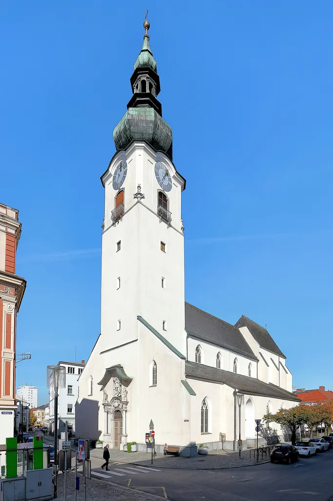 Südwestansicht der Stadtpfarrkirche Hl. Johannes Evangelist in der oberösterreichischen Stadt Wels.Ursprünglich war sie eine romanische Basilika und Ende des 13. Jahrhunderts begann ein gotische Umbau und Erweiterung. In der ersten Hälfte des 18. Jahrhundert erfolgte eine Turmerhöung und das barocke Westportal wurde errichtet. Anlässlich dem 1000-jährigen urkundlichen Bestehen der Kirche, wurde sie 1888 bis 1890 erneuert und umgebaut. Bei der Restaurierung 1958 wurden diese Veränderungen teilweise rückgängig gemacht.
