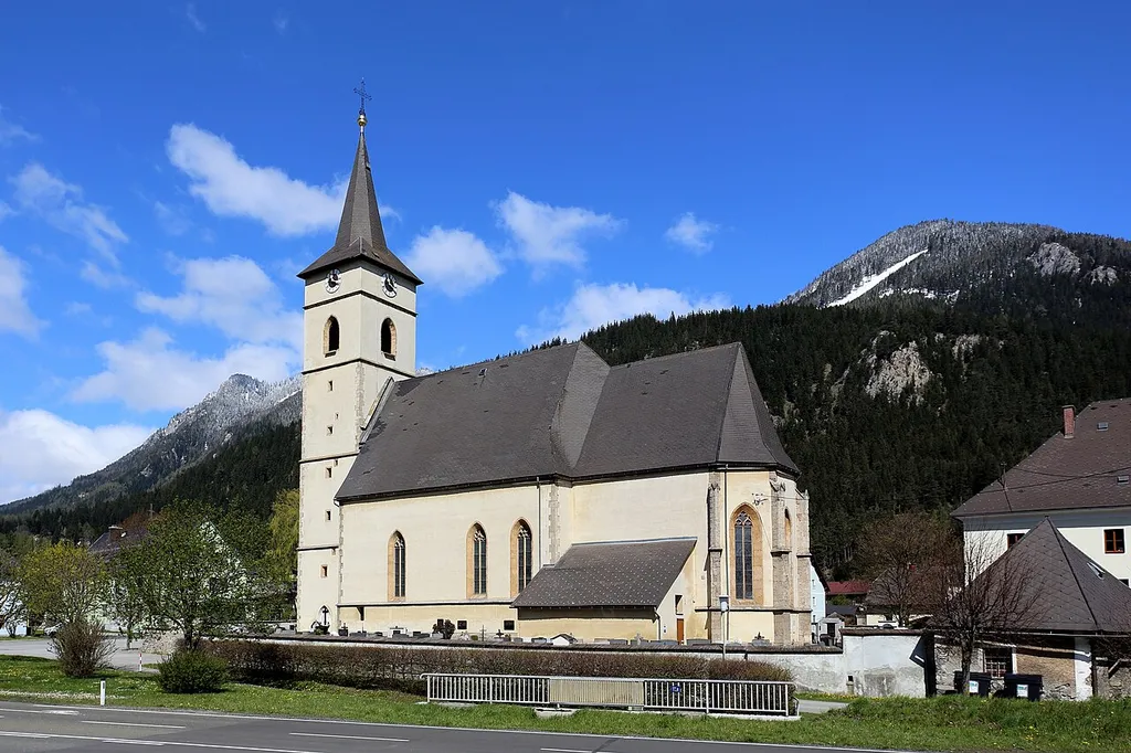 Südostansicht der Pfarrkirche hl. Johannes der Täufer in der steiermärkischen Marktgemeinde Kammern im Liesingtal. Die spätgotische Kirche befindet sich am südlichen Ortsrand und ist von einem teilweise ummauerten Friedhof umgeben. Im Sommer 1480 wurde die Vorgängerkirche bei einem Türkeneinfall zerstört. Danach wurde der Sakralbau wieder aufgebaut, erweitert und 1510 geweiht. Der achteckige Turmhelm des quadratischen, vorgestellten Westturmes stammt aus dem Ende des 19. Jahrhunderts. In der südlich angebauten Sakristei, die teilweise ein Teil des romanischen Vorgängerbaues ist, befinden sich am Tonnengewölbe noch schlecht erhaltene Fresken aus dem 13. Jahrhundert. Zur Barockzeit wurde nördlich eine kleine Kapelle angebaut.