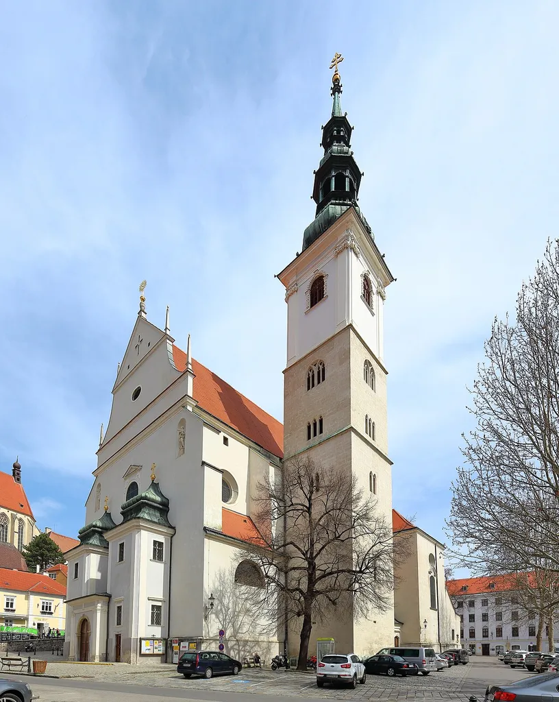 Südwestansicht der römisch-katholischen Pfarrkirche hl. Veit in der niederösterreichischen Stadt Krems an der Donau.Die Kirche wurde von 1616 bis 1630 nach Plänen der Baumeister Cypriano Biasino und Johann Baptist Spazio gebaut und war einer der ersten Barockkirchen nördlich der Alpen. Die Sakralbau besteht aus einem Langhaus mit acht Seitenkapellen, einem Querschiff und einem etwas niedrigeren Chor mit Rundapsis. Die Grabplatten an den Außenmauern erinnern an den ehemaligen alten Friedhof rund um die Kirche. In den Neubeu wurde teilweise der Turm der mittelalterlichen Vorgängerkirche miteinbezogen.