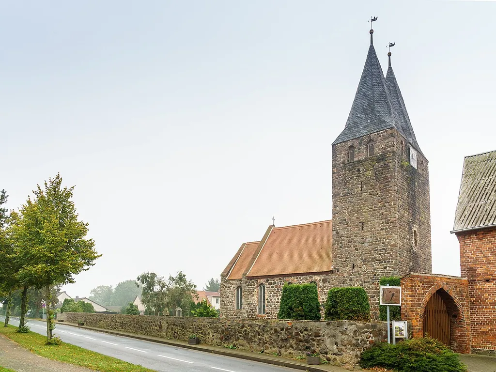 Kirche, mit einem in der Friedhofsmauer teilweise eingemauerten Gotisches Kreuz in Rochau OT Klein Schwechten