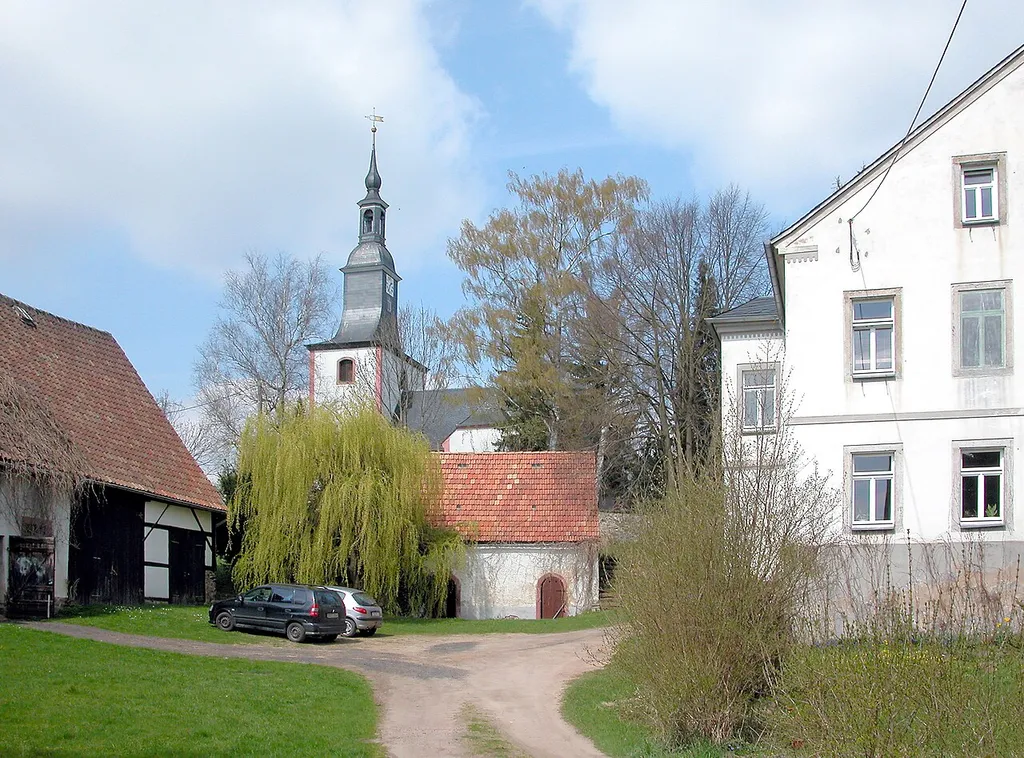 22.04.2010 04736 Reinsdorf (Waldheim): Dorfkirche (GMP: 51.060966,12.969976). Die Umfassungsmauern sind teilweise mittelalterlichen Ursprungs. Das Portal an der Südseite wurde um 1470 in reicher Profilierung aus Rochlitzer Porphyr gefertigt. Der Vorgängerbau wurde 1676 teils abgebrochen, teils umgebaut. Über den mfassungsmauern, die größtenteils stehen blieben, zog man ein Tonnengewölbe ein, welches das gesamte Kirchenschiff überdeckt. Der romanische Westturm blieb stehen, wurde aber durch den Einbau zweier Bogenöffnungen zum Kirchenraum gezogen. So entstand ein rechteckiges Gebäude mit breitem Westturm. Die Turmbekrönung wurde mehrfach erneuert, zuletzt 1825. Der Kernbau wird durch jüngere Anbauten erweitert. An der Nordseite wurde die Sakristei angefügt, während an der Südseite 1767 eine Herrschaftsloge entstand. Sicht ais dem Pfarrhof von Süden. [DSCN41659.TIF]20100422250DR.JPG(c)Blobelt