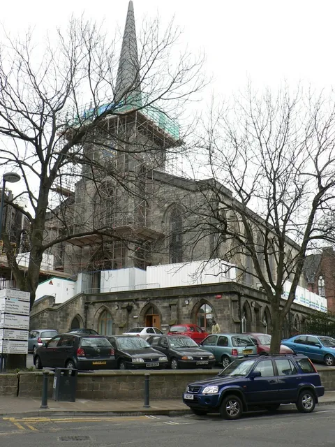 St George's parish church, Great George Street, Leeds, West Yorkshire, seen from the southwest. St George's church was built with a spire and four pinnacles around its base. In 1962 a storm damaged the spire and some of the pinnacles fell through the church roof. The spire was demolished as the parish did not have the funds to repair both it and roof. A new spire was built in 2006, funded by the developers of a block of apartments next to the church. (Apparently it was a condition of planning permission.) This picture is an attempt to recreate an old picture on the Leodis website which includes the original spire. However, the Centaur building was built later, and foiled this plan. This picture was taken with the photographer's back against the Centaur building. The original spire was taller than its replacement. See the picture on Leodis here http://www.leodis.net/display.aspx?id=2003213_38058108